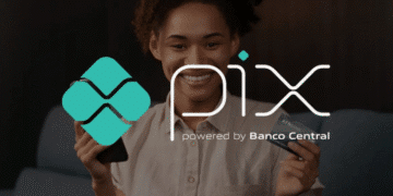 Mulher segurando celular e cartão com logo do Pix ao lado.