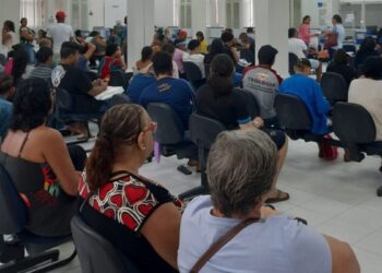 Público aguardando atendimento em cadeiras pretas na sala de espera de uma agência do INSS durante mutirão, visando agilizar a análise de benefícios.