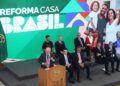 Presidente discursando no lançamento do programa 'Reforma Casa Brasil', com um telão exibindo famílias felizes e autoridades presentes.