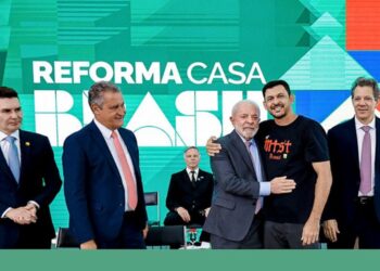 Presidente Lula abraça um homem vestindo a camisa do MTST em evento de lançamento do programa "Reforma Casa Brasil", ao lado de ministros e autoridades, simbolizando o apoio do governo à reforma de moradias.