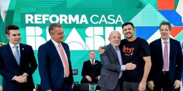Presidente Lula abraça um homem vestindo a camisa do MTST em evento de lançamento do programa "Reforma Casa Brasil", ao lado de ministros e autoridades, simbolizando o apoio do governo à reforma de moradias.
