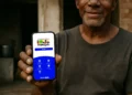Homem segurando smartphone com tela do aplicativo Bolsa Família, do programa social da Caixa Econômica.