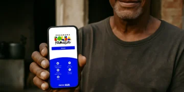 Homem segurando smartphone com tela do aplicativo Bolsa Família, do programa social da Caixa Econômica.