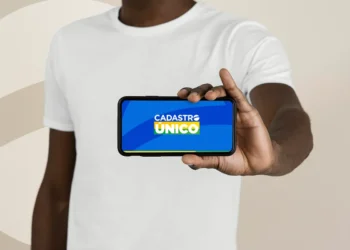 Pessoa segurando smartphone com a logo do CadÚnico na tela, ilustrando o acesso a vagas de capacitação profissional.