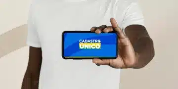 Pessoa segurando smartphone com a logo do CadÚnico na tela, ilustrando o acesso a vagas de capacitação profissional.