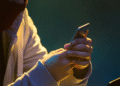 Pessoa usando um smartphone em ambiente escuro, com parte do rosto coberta, simbolizando fraude ou uso indevido de informações em golpes online.
