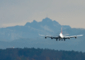 Avião comercial de grande porte aterrissando com montanhas e floresta ao fundo, simbolizando viagem aérea