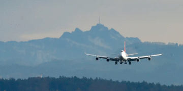 Avião comercial de grande porte aterrissando com montanhas e floresta ao fundo, simbolizando viagem aérea