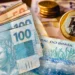 Notas de R$ 100 e moedas de R$ 1, representando o valor de R$ 7.075,83 do salário mínimo ideal calculado pelo DIEESE.