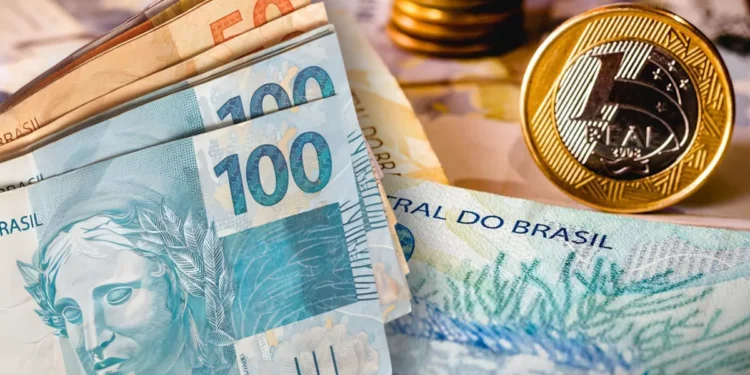 Dinheiro em espécie com notas de 100 e 50 reais e moedas de real amareladas em fundo desfocado