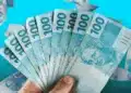 Uma mão segura um leque de notas de cem reais, simbolizando os prêmios em dinheiro sorteados para consumidores.