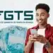 Homem sorridente segurando celular com notas de cem reais ao lado e logo do FGTS ao fundo