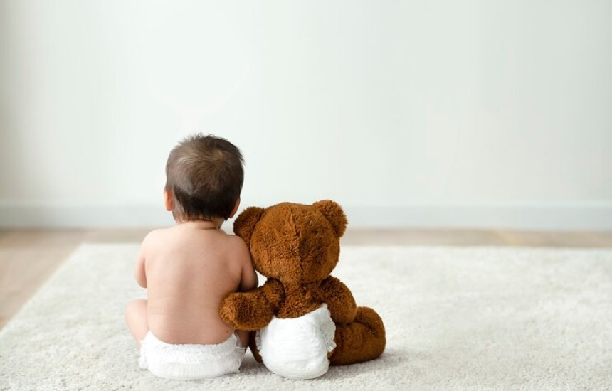 Bebê e ursinho de pelúcia, simbolizando o apoio necessário aos filhos de vítimas de feminicídio, beneficiários da pensão especial do INSS.