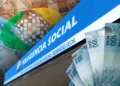 Imagem do INSS com destaque para o pagamento de benefícios, ilustrada com cédulas de 100 reais e o prédio do Instituto Nacional do Seguro Social. Benefícios podem chegar a R$ 8.157,41 em outubro.