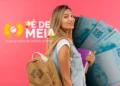 Estudante feliz com mochila e livros e notas de R$ 100 ao fundo simbolizando o benefício Pé de Meia
