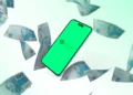 Smartphone exibindo o logotipo do Pix em uma tela verde, cercado por notas de 100 reais flutuando, representando transações financeiras e impostos.