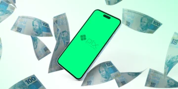 Smartphone exibindo o logotipo do Pix em uma tela verde, cercado por notas de 100 reais flutuando, representando transações financeiras e impostos.