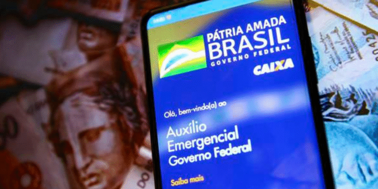 Celular exibindo a tela do aplicativo do Auxílio Emergencial do Governo Federal, com notas de real ao fundo.
