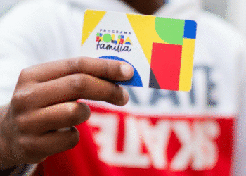 Mão segurando o cartão colorido do Programa Bolsa Família.