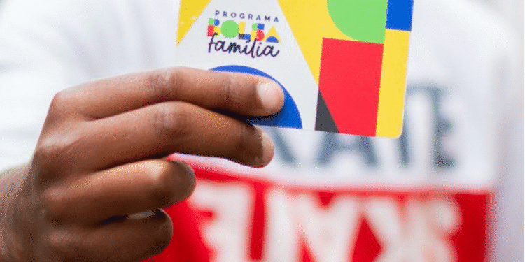 Mão segurando o cartão colorido do Programa Bolsa Família.