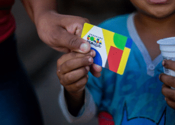 Cartão do Bolsa Família sendo segurado por uma criança