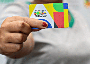 Cartão do programa Bolsa Família sendo segurado por uma pessoa.