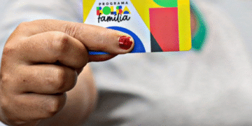 Cartão do programa Bolsa Família sendo segurado por uma pessoa.