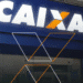 Fachada da agência da Caixa Econômica Federal com logo iluminado.