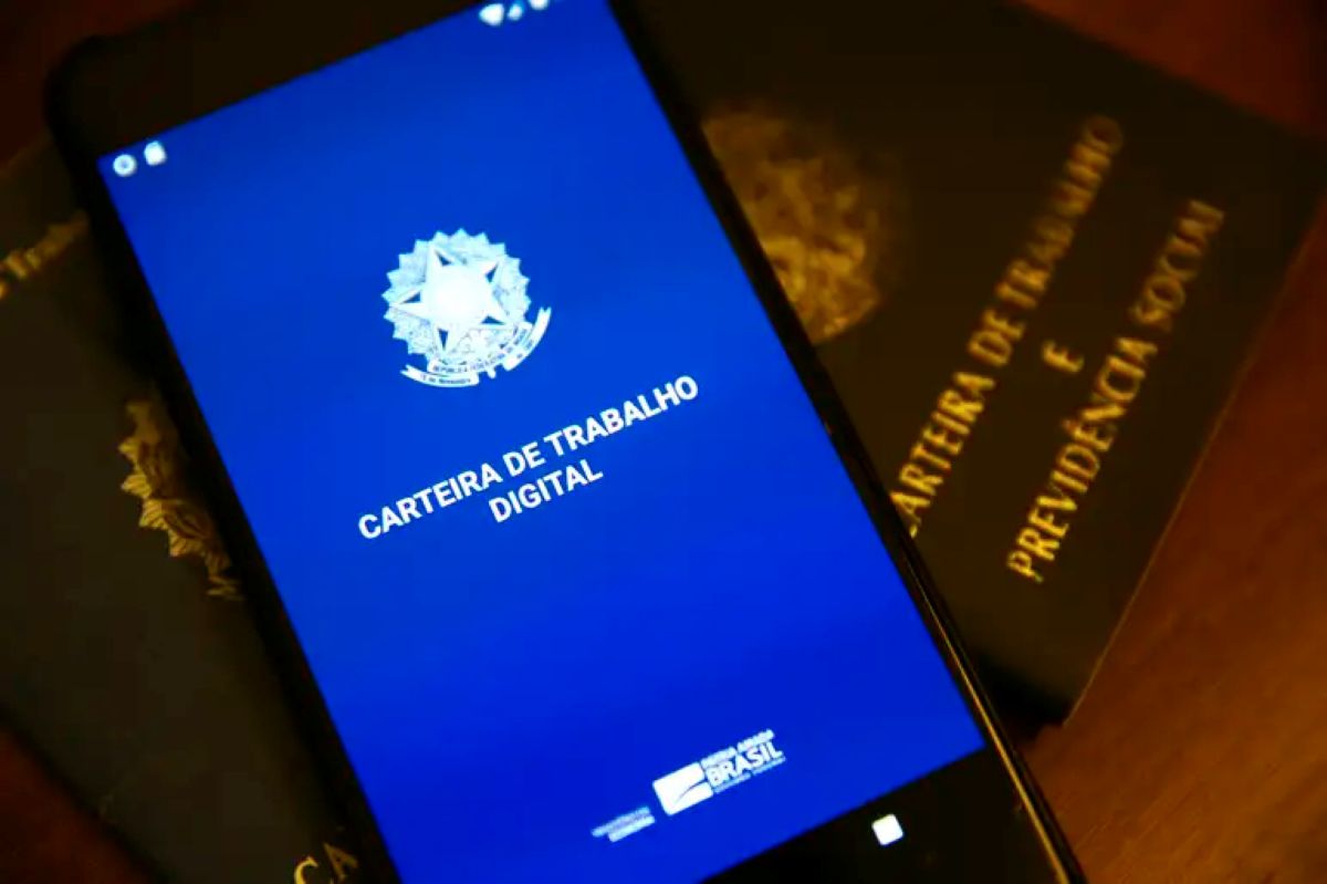 PIS/PASEP 2026: Guia Completo para Consulta por CPF na Carteira Digital Tela de smartphone exibindo a Carteira de Trabalho Digital, com carteiras físicas ao fundo, simbolizando a consulta do PIS/PASEP por CPF.