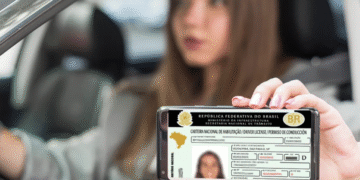 Mulher segurando a CNH digitalizada em um smartphone dentro do carro