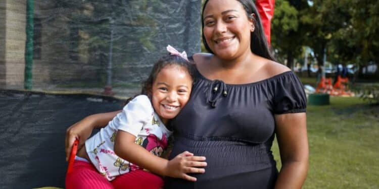 Mãe abraça a filha pequena enquanto coloca a mão na barriga de gestante, simbolizando as beneficiárias do Programa Mães de Pernambuco.