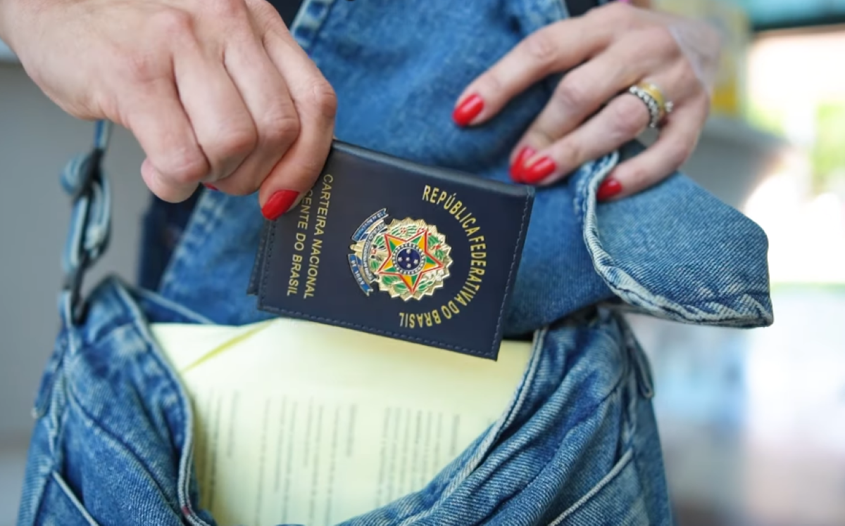 Pessoa guardando carteira da Carteira Nacional Docente do Brasil na bolsa.