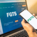 Pessoa acessando informações do FGTS pelo celular e computador.