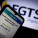 Tela de celular mostra saldo do FGTS e opção de saque, com logotipo do FGTS Digital ao fundo.