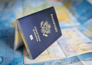 Passaporte americano aberto com carimbos de vistos sobre um mapa, simbolizando o processo de solicitação de visto para os EUA.