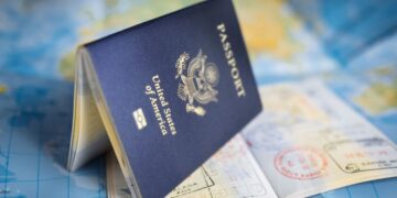Passaporte americano aberto com carimbos de vistos sobre um mapa, simbolizando o processo de solicitação de visto para os EUA.