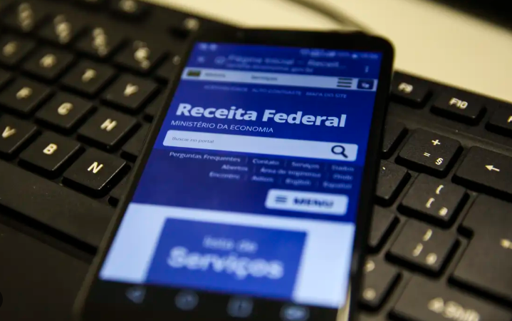 Smartphone sobre teclado exibindo o site da Receita Federal.