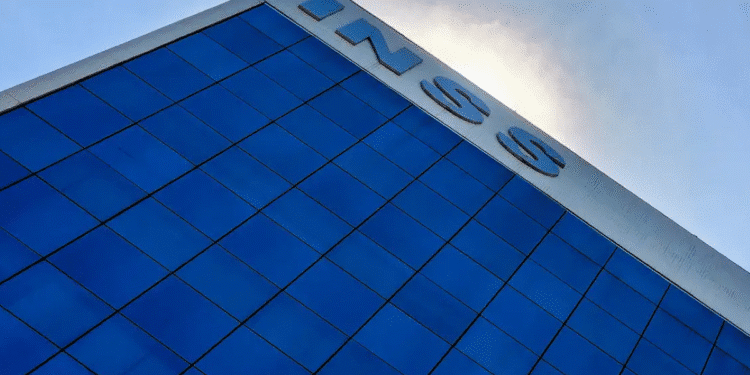 Fachada de prédio com o logo do INSS em destaque, sob céu azul, representando a instituição
