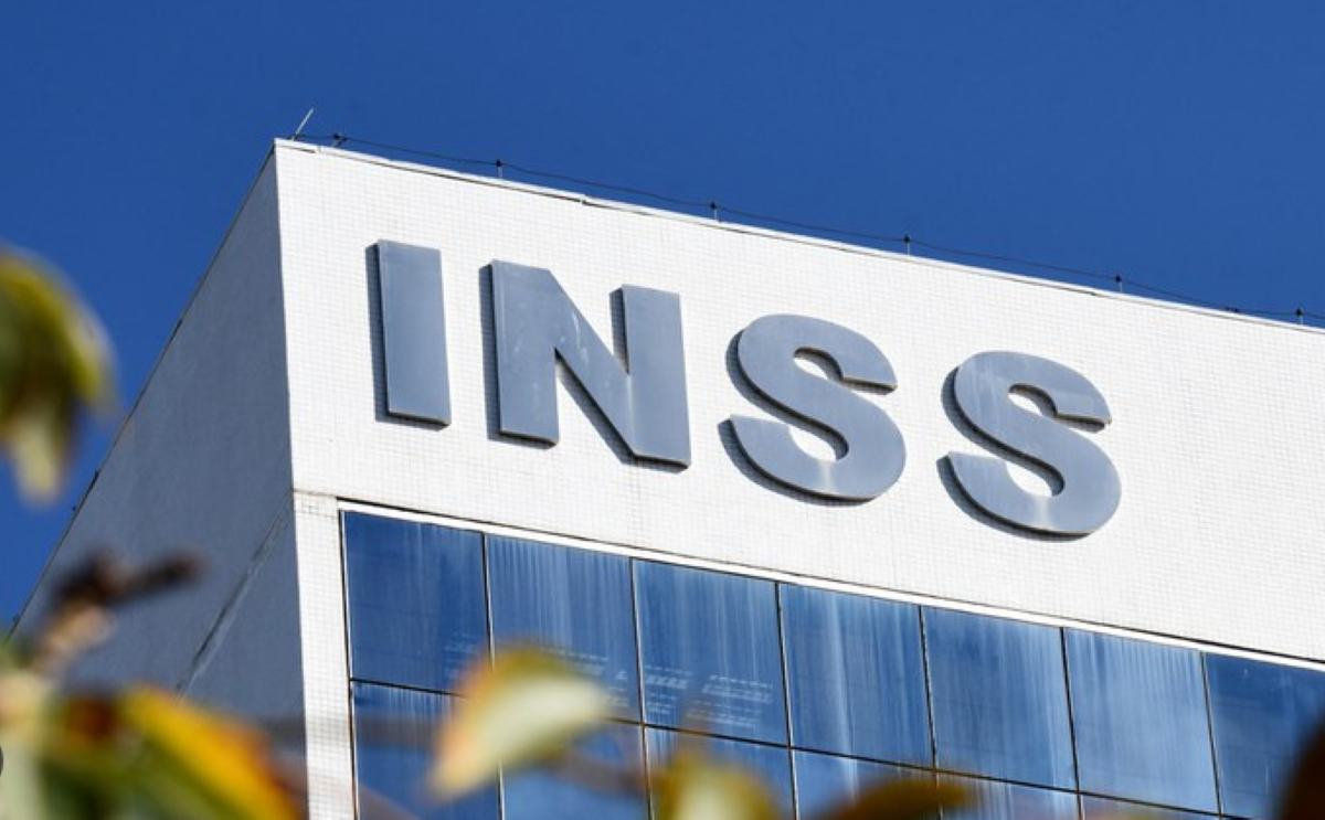 Fachada de prédio com a sigla INSS em destaque contra céu azul.