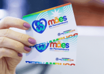 Mão segurando cartões coloridos do programa Mães de Pernambuco, com logotipo e nome do governo estadual.
