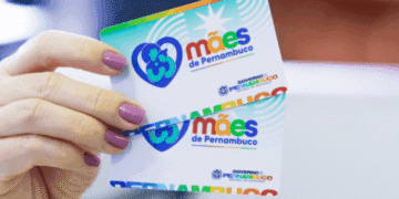 Mão segurando cartões coloridos do programa Mães de Pernambuco, com logotipo e nome do governo estadual.