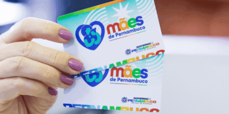 Mão segurando cartões coloridos do programa Mães de Pernambuco, com logotipo e nome do governo estadual.