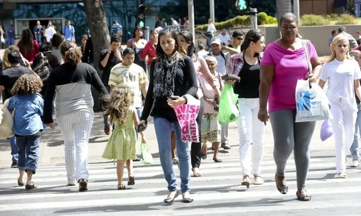Mulheres diversas atravessam uma faixa de pedestres em uma cidade movimentada, simbolizando o fluxo e a entrada no mercado de trabalho e nas novas oportunidades.