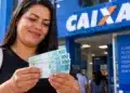 Abono salarial: mais de 1 milhão de trabalhadores recebem lote complementar a partir de hoje (15) 3 Mulher confere cédulas de R$ 100 em frente a uma agência da Caixa, representando o pagamento do lote complementar do Abono Salarial.