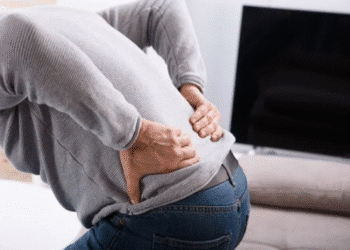 Pessoa com dor nas costas segurando a região lombar.