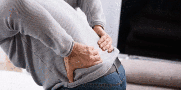 Pessoa com dor nas costas segurando a região lombar.