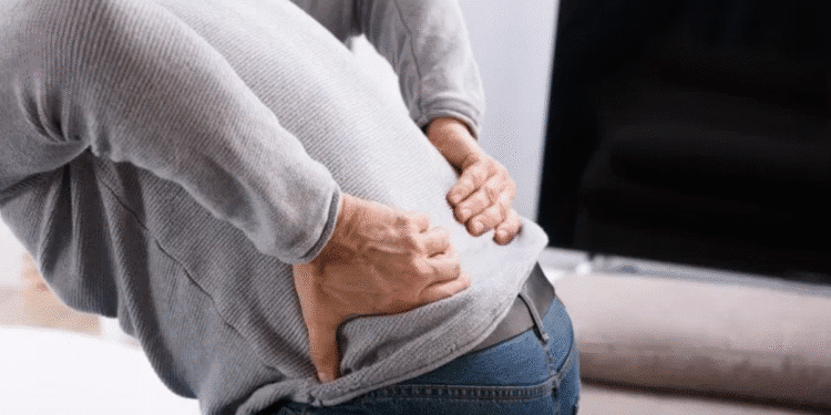 Pessoa com dor nas costas segurando a região lombar.