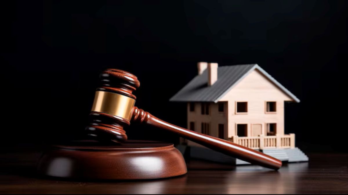 Um martelo de leilão (mallet) ao lado de uma pequena casa em miniatura, simbolizando o processo de leilões imobiliários do Itaú e as etapas para participação.