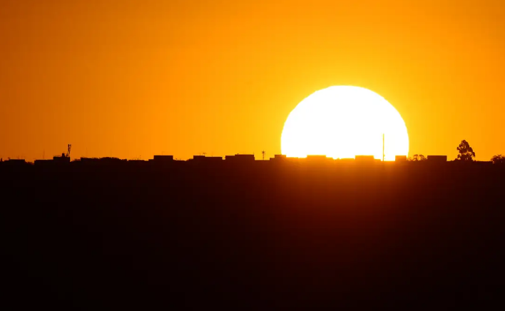 Pôr do sol com silhueta de prédios e céu alaranjado