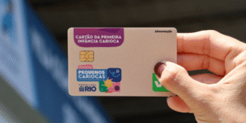 Cartão do programa Primeira Infância Carioca sendo segurado pela mão de uma pessoa.